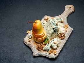Slice of French Roquefort cheese and figs on wooden cutting board
