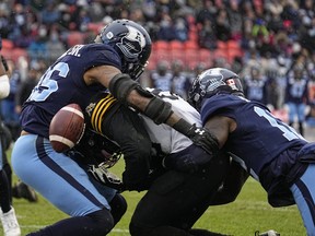Hamilton Tiger-Cats wide receiver Steven Dunbar Jr. (82) fumbles the ball as he is hit by Toronto Argonauts linebacker Dexter McCoil (26) and defensive back Jamal Peters (12) during the Eastern Conference Final at BMO Field.