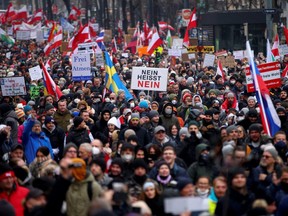Demonstrators hold flags and placards as they march to protest against the COVID-19 restrictions and the vaccine mandate in Vienna, Austria, Saturday, Dec. 11, 2021.