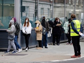 People wait in a queue outside University College London Hospital vaccination centre to receive a COVID-19 vaccine or booster in London, England, Friday, Dec. 17, 2021.