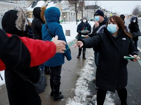City of Ottawa staff hand out wrist bands to people waiting to pick up COVID-19 antigen test kits as the latest Omicron variant emerges as a threat, in Ottawa, Dec. 21, 2021.