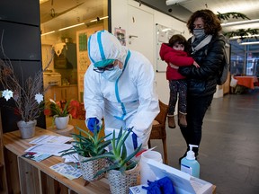 A healthcare worker prepares to conduct a PCR Covid-19 test on Ona, 2 years old, accompanied by her mother Ines, after a confirmed case of Covid-19 in her nursery, in Barcelona, on December 2, 2021.