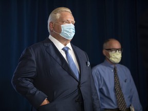 Ontario Premier Doug Ford (left) stands alongside  Dr. Kieran Moore, the Chief Medical Officer of Health of Ontario, during a press briefing at the Queens Park Legislature in Toronto, on Friday, October 15, 2021.