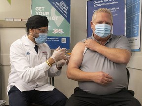 Ontario Premier Doug Ford receives his COVID-19 booster shot from pharmacist Anmol Soor, at a Shoppers Drug Mart in Etobicoke, Ont. on Tuesday, December 21, 2021.