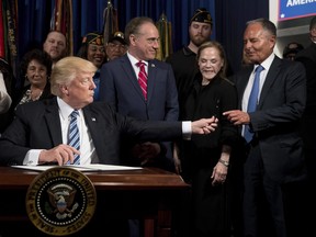 Laura Perlmutter, second from right, watches as then U.S. President Donald Trump, left, accompanied by Veterans Affairs Secretary David Shulkin, centre, hands his pen to Isaac "Ike" Perlmutter, an Israeli-American billionaire, and the CEO of Marvel, right, after signing an Executive Order on "Improving Accountability and Whistleblower Protection" at the Department of Veterans Affairs, April 27, 2017, in Washington.