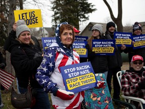Supporters hold posters regarding critical race theory as people gather to attend a "Let's Go Brandon Festival" rally, in the Brandon Township village of Ortonville, Michigan, November 20, 2021.
