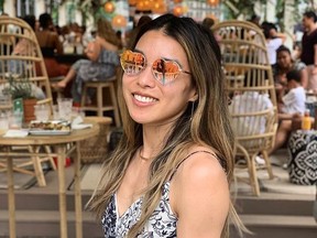 Smiling woman wearing heart-shaped mirrored sunglasses.