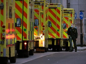 An ambulance crew member is seen alongside ambulances parked outside the Royal London hospital in London, England, Tuesday, Dec. 28, 2021.