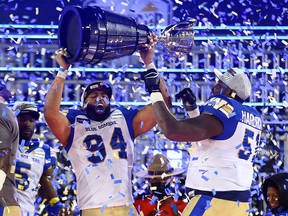 Jackson Jeffcoat and Jermarcus Hardrick of the Winnipeg Blue Bombers celebrate victory with the Grey Cup after beating the Hamilton Tiger-Cats at Tim Hortons Field on December 12, 2021 in Hamilton.