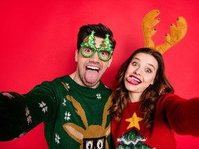 Photo of childish lady and guy at newyear costume party making selfies wear ugly knitted pullovers isolated red color background