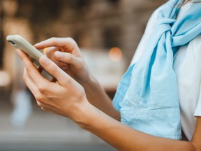 Close-up photo of female hands with smartphone. Young woman typing on a mobile phone on a street