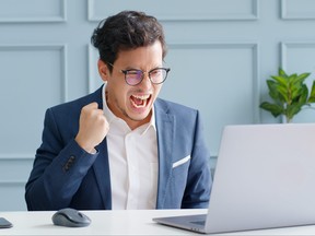 Excited young businessman feeling surprise and happy receiving great news from laptop,