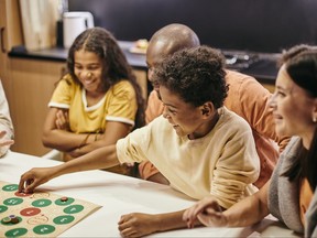 Cute cheerful boy putting chip on number of board game