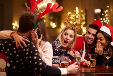 Couple Kissing In Bar As Friends Enjoy Christmas Drinks
