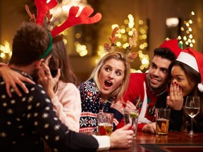Couple Kissing In Bar As Friends Enjoy Christmas Drinks