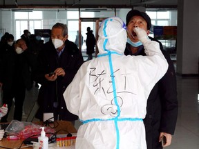 A medical worker in protective suit collects a swab sample from a man for nucleic acid testing at a residential compound, during another round of mass testing following the coronavirus disease (COVID-19) outbreak in Xian, Shaanxi province, China December 27, 2021.
