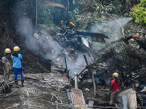 Firemen and rescue workers stand next to the debris of an IAF Mi-17V5 helicopter crash site in Coonoor, Tamil Nadu, on December 8, 2021.