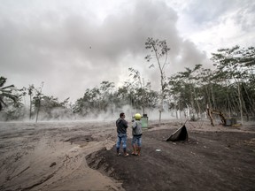 Volunteers look as volcanic ash spews from Mount Semeru volcano during an eruption in Sumber Wuluh village, Lumajang, East Java province, Indonesia Dec. 5, 2021, in this photo taken by Antara Foto.