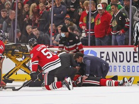 Jujhar Khaira of the Chicago Blackhawks is tended to on the ice after a collision in the second period against the New York Rangers at the United Center on Dec. 7, 2021 in Chicago, Ill.