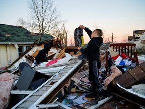 Creed, 9, inspects debris while climbing through the wreckage to recover belongings, from a home where a toddler died the night of the storm, in Mayfield, Kentucky, December 12, 2021.