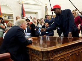 Rapper Kanye West shows U.S. President Donald Trump his mobile phone during a meeting in the Oval Office at the White House in Washington, D.C., Oct. 11, 2018.