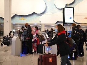 Travelers wear masks at LaGuardia International Airport on November 30, 2021 in New York as concern grows worldwide over Omicron, the newest Covid-19 variant.