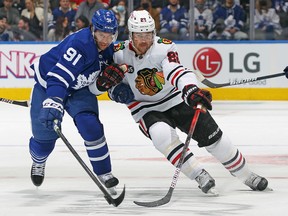 Ryan Carpenter of the Chicago Blackhawks battles for the puck against John Tavares of the Toronto Maple Leafs during an NHL game at Scotiabank Arena on December 11, 2021 in Toronto.