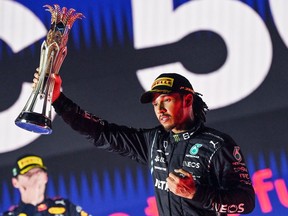 Winner Mercedes' British driver Lewis Hamilton, right, reacts with his trophy flanked by second-placed Red Bull's Dutch driver Max Verstappen during the podium ceremony after the Formula One Saudi Arabian Grand Prix at the Jeddah Corniche Circuit in Jeddah on Dec. 5, 2021.
