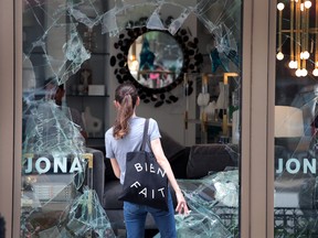 A woman looks through the shattered glass window of the Jonathan Adler interior design store that was looted on August 10, 2020 in Chicago, Illinois.