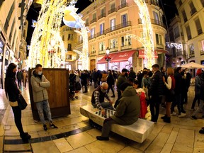 Men play chess as people gather as Christmas lights are turned on to mark the start of the Christmas season at Marques de Larios street, amid the coronavirus disease (COVID-19) pandemic, in downtown Malaga, Spain, November 26, 2021.