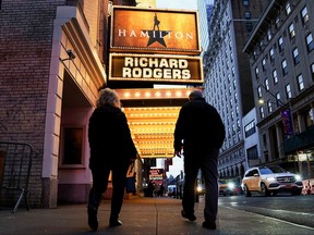 People walk past the Richard Rodgers Theatre after cancellations of the Hamilton broadway shows due to breakthrough COVID-19 cases in New York City, Dec. 16, 2021.