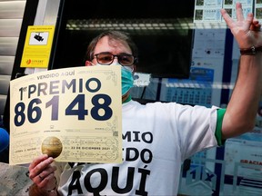 Lottery seller Javier Monino shows the winning number of the first prize in Spain's Christmas lottery "El Gordo" (The Fat One), amid the COVID-19 outbreak, in Madrid, Spain, Dec. 22, 2021.