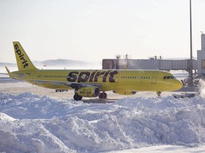 A Spirit Airlines airplane prepares to drive around a large snow pile at Boston's Logan International Airport,  Jan. 5, 2018.