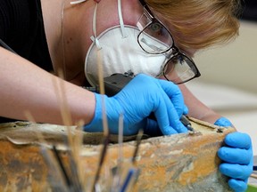 Chelsea Blake, a conservator with the Virginia Department of Historic Resources, attempts to open what is believed to be a time capsule found in Confederate General Robert E. Lee's monument, which was buried in 1887, in Richmond, Virginia, December 22, 2021.