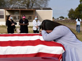 Lila Blanks holds the casket of her husband, Gregory Blanks, 50, who died of COVID-19, ahead of his funeral in San Felipe, Texas, Jan. 26, 2021.