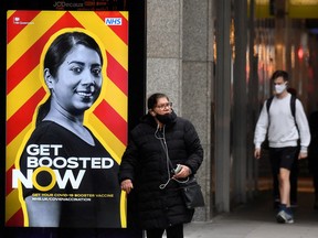 People walk past a government health campaign advertisement encouraging people to take a vaccine booster dose, at a bus stop, amid the spread of the COVID-19 pandemic, in London, Dec. 17, 2021.