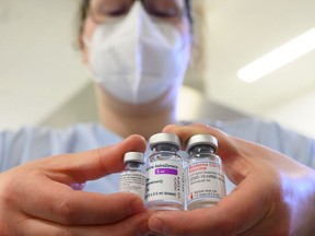 A woman wearing a face mask shows three vials with different vaccines against Covid-19 by (L-R) Pfizer-BioNTech, AstraZeneca and Moderna in the pharmacy of the vaccination center at the Robert Bosch hospital in Stuttgart, southern Germany, on February 12, 2021, amid the novel coronavirus / COVID-19 pandemic.