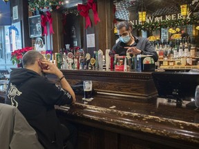 Tim Rowhani pours a pint behind the bar at McKibbinâ€™s Irish Pub on St-Laurent Boulevard in Montreal, Monday, December 20, 2021, as the COVID-19 pandemic continues in Canada and around the world.