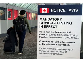 A traveler walks past a "Mandatory COVID-19 Testing" sign at Pearson International Airport during the coronavirus disease (COVID-19) pandemic of Toronto, Ontario, Canada, December 18, 2021.  REUTERS/Carlo Allegri