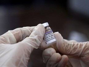 A health worker holds a vial of the "Comirnaty" Pfizer-BioNTech COVID-19 vaccine at a vaccination center in Karachi, Pakistan December 2, 2021.