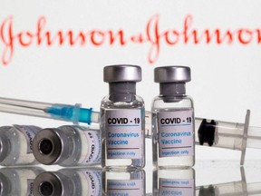 Vials labeled "COVID-19 Coronavirus Vaccine" and syringe are seen in front of displayed Johnson & Johnson logo in this illustration taken, February 9, 2021.
