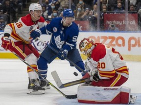 Calgary Flames goaltender Dan Vladar makes a save as defenceman Nikita Zadorov tries to control Toronto Maple Leafs left wing Michael Bunting during second period NHL action in Toronto on Friday November 12, 2021.