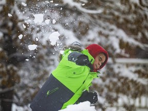 Diego Ibarra, 7, has some fun in the snow with his dad at Clarence Square Park in downtown Toronto, Nov. 28, 2021.