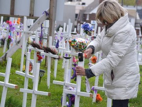 Denise Sandul drives a new cross into the ground at the memorial site for victims of opioid-related death in downtown Sudbury on Oc.t 24, 2021. Five crosses were added, bringing the total at the time to 214.