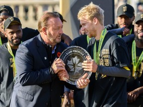 Forge FC Captain Kyle Bekker receives the Canadian Premier League trophy from CPL Commissioner David Clanachan after winning the second game of finals against Cavalry FC at ATCO Field at Spruce Meadows on Saturday, November 2, 2019.