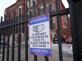 A sign on the fence outside of Lowell elementary school asks students, staff and visitors to wear a mask to prevent the spread of COVID-19 on January 5, 2022 in Chicago.