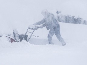 A homeowner attempts to clear snow from a driveway in Ajax on Jan. 17, 2022.