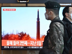 People walk past a television screen showing a news broadcast with file footage of a North Korean missile test, at a railway station in Seoul on Jan. 11, 2022, after North Korea fired a "suspected ballistic missile" into the sea, South Korea's military said, less than a week after Pyongyang reported testing a hypersonic missile.