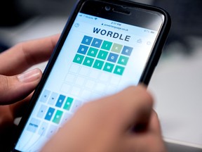 A photo illustration showing a person playing online word game "Wordle" on a cellphone.