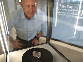 Aaron Celestian, curator of the Mineral Sciences at the Natural History Museum, looks at a 555.55 carat black diamond named The Enigma before it is auctioned at Sotheby's in Beverly Hills, California January 26, 2022.